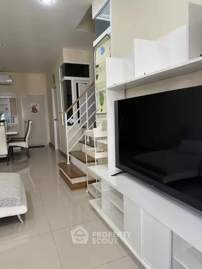 Modern living room with sleek TV unit and elegant staircase in stylish home