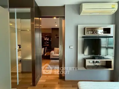 Modern living room with wall-mounted TV and air conditioning in stylish apartment.