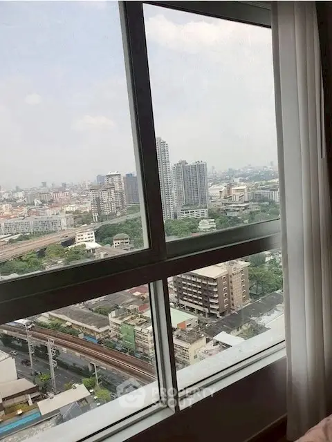 Stunning cityscape view from high-rise apartment window, showcasing urban skyline and lush greenery.