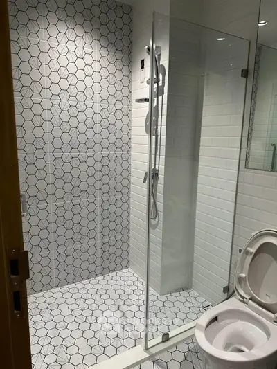 Modern bathroom with geometric tile design and glass shower enclosure