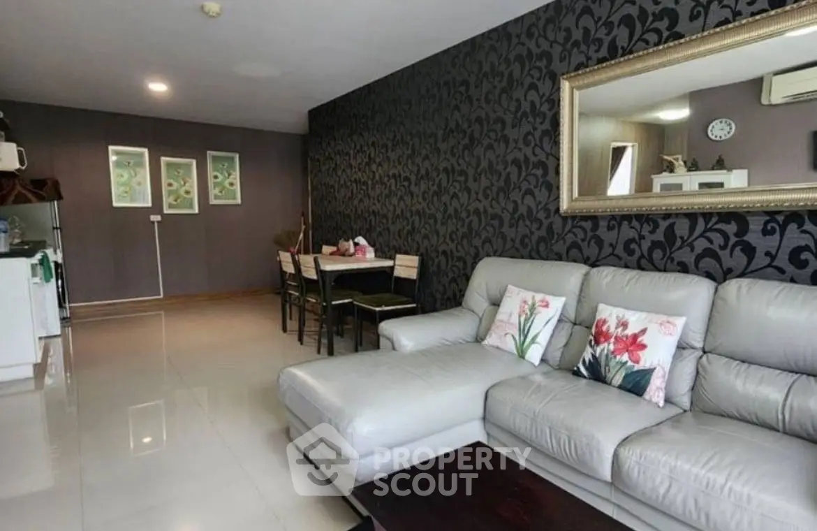Stylish living room with modern decor and elegant wallpaper, featuring a cozy sectional sofa and dining area.