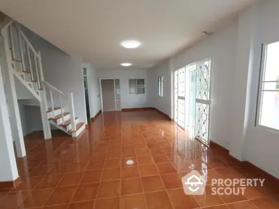 Spacious open-plan living room with tiled flooring and natural light