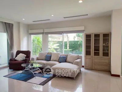 Spacious living room with modern furniture and large windows offering garden views.
