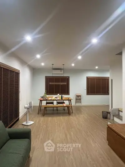 Spacious living room with modern decor and wooden flooring, perfect for family gatherings.