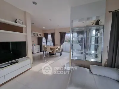 Spacious open-plan living room with modern kitchen and dining area, featuring large windows and sleek furnishings.