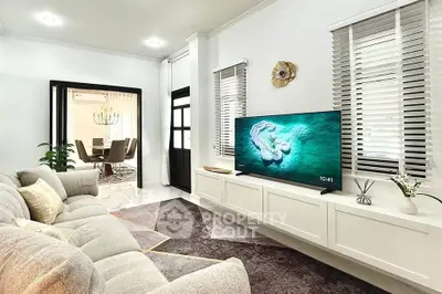 Modern living room with cozy sofa and large TV, open view to dining area