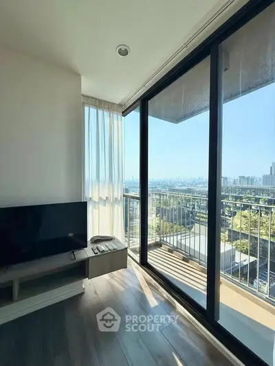 Modern living room with floor-to-ceiling windows and stunning city view from balcony.