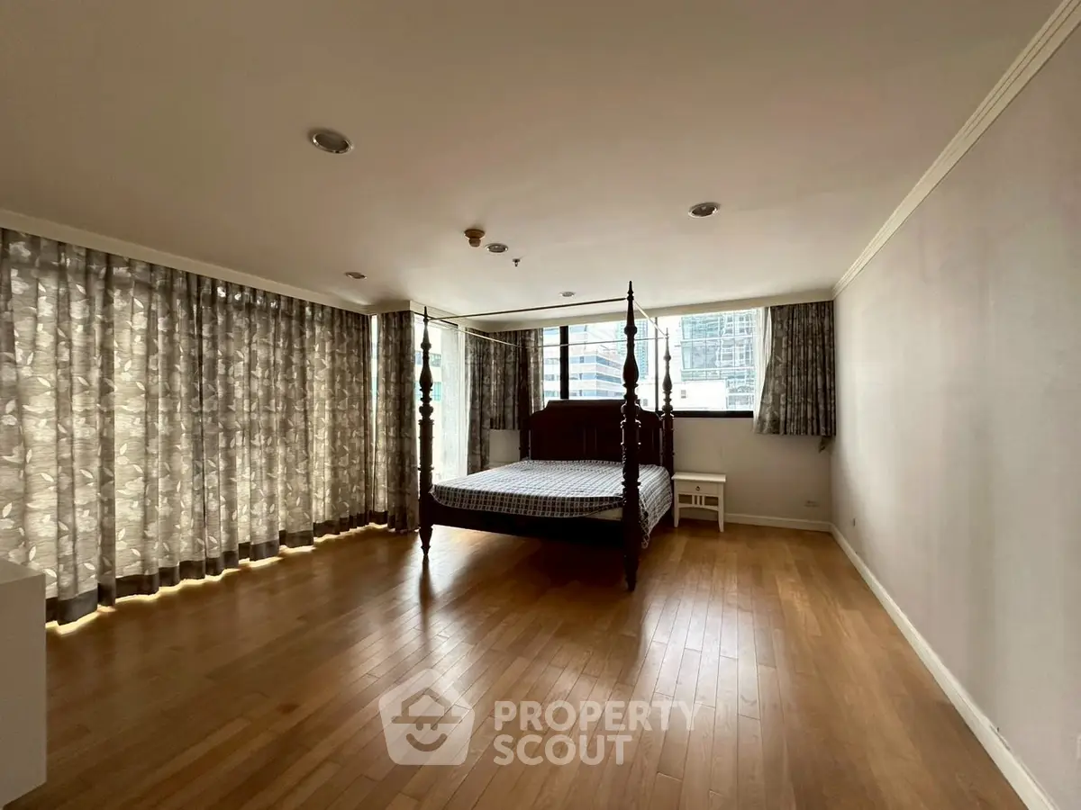 Spacious bedroom with large windows and elegant wooden flooring