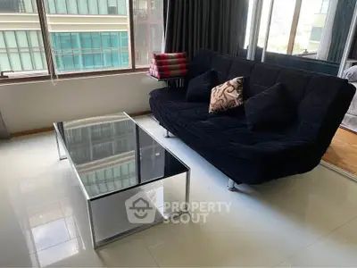 Modern living room with sleek glass coffee table and stylish black sofa in a high-rise apartment.