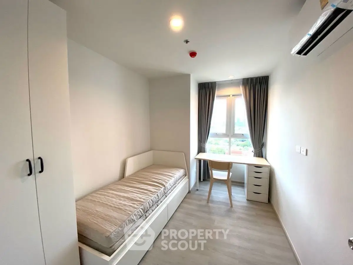 Modern minimalist bedroom with single bed, desk, and large window offering city view.