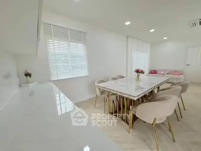Elegant dining area with marble table and plush chairs in modern open-plan living space.