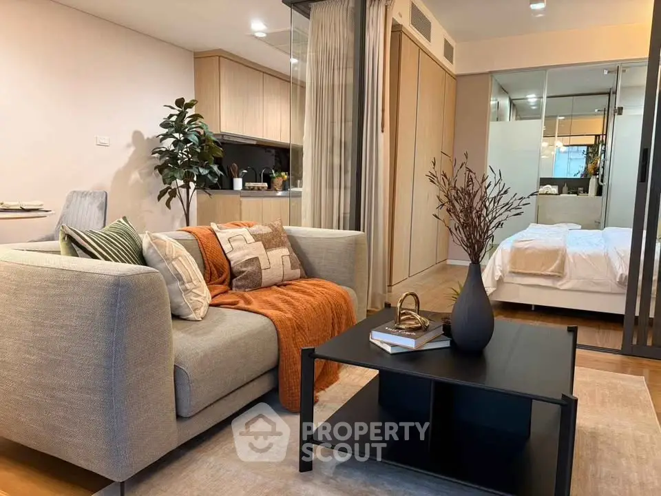 Modern open-plan living room with cozy sofa and stylish decor adjacent to a sleek kitchen and bedroom.