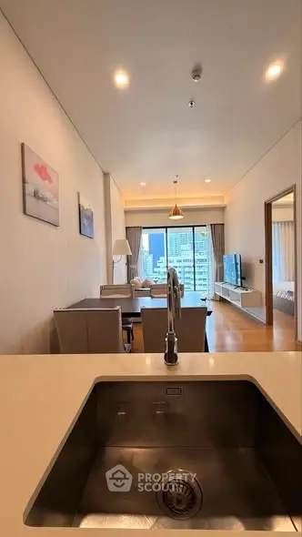 Modern open-plan living room with city view, featuring sleek kitchen sink and stylish decor.