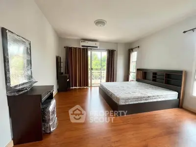 Spacious bedroom with wooden flooring and large windows for natural light