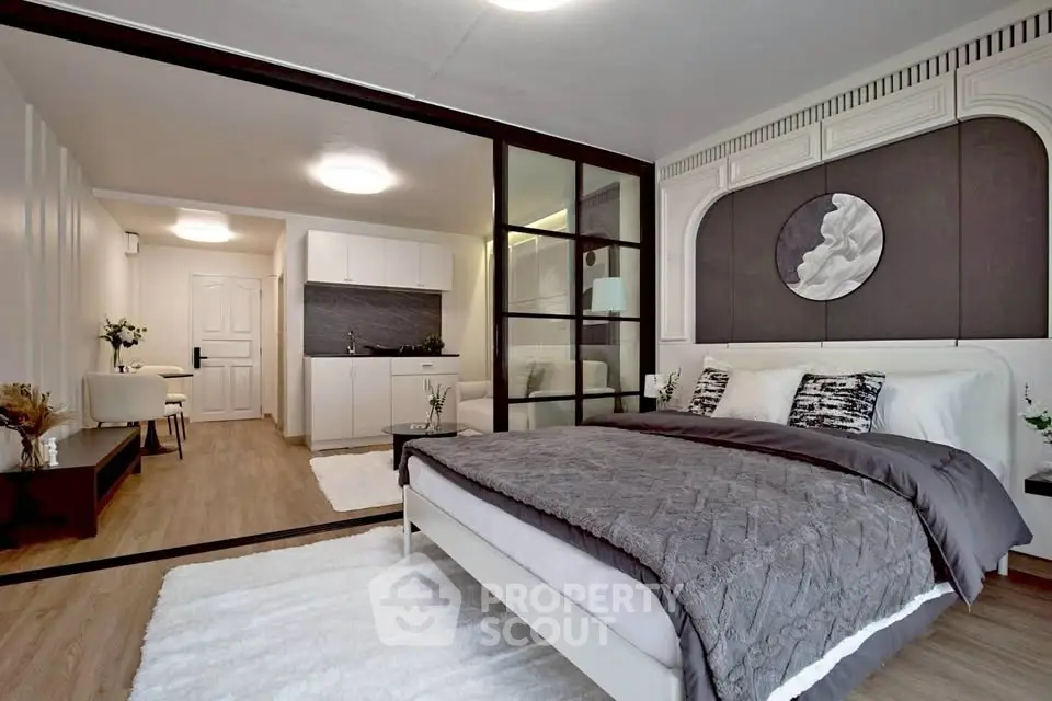 Modern bedroom with open layout and stylish decor, featuring a cozy bed and sleek kitchenette.