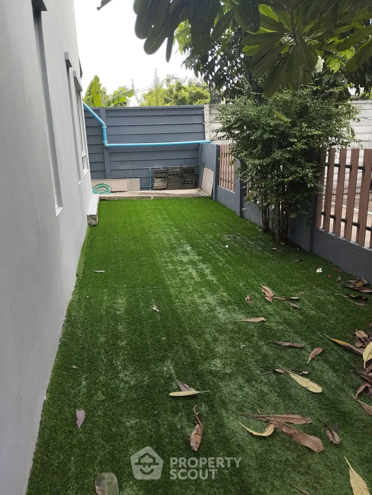 Charming backyard with lush artificial grass and privacy fence, perfect for outdoor relaxation.