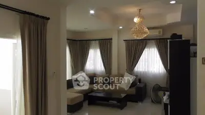 Elegant living room with chandelier and large windows, featuring a cozy sectional sofa and stylish curtains.