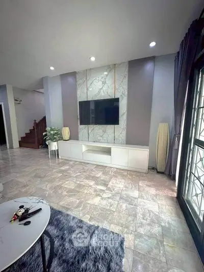 Spacious living room with modern decor and large TV, featuring elegant marble accents.