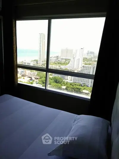 Stunning bedroom with panoramic city and ocean views from a high-rise window.
