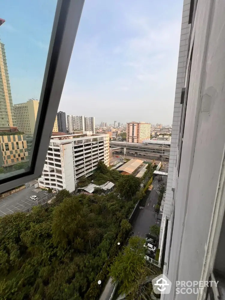 Stunning urban view from high-rise building window showcasing cityscape and greenery.