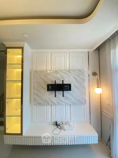 Modern living room with elegant wall paneling and TV mount, featuring built-in shelving and ambient lighting.