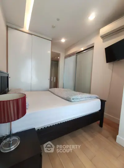Modern bedroom with sleek design, featuring a comfortable bed, stylish lamp, and ample closet space.