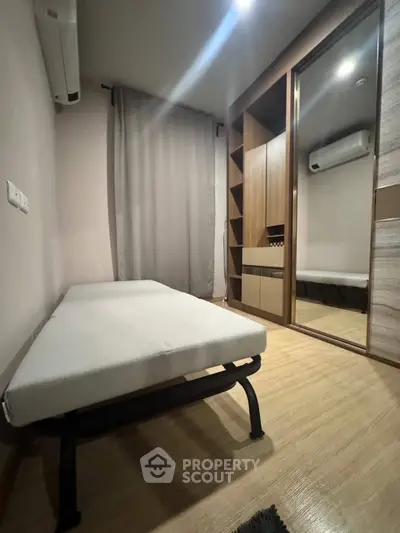 Cozy bedroom with minimalist design, featuring a single bed, mirrored wardrobe, and air conditioning.