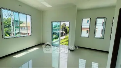 Bright and airy living room with large windows and balcony access, offering a serene view of the neighborhood.