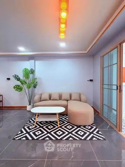 Modern living room with stylish sofa, geometric rug, and elegant lighting.