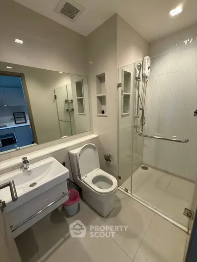 Modern bathroom with glass shower and sleek fixtures in contemporary apartment.