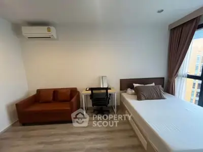 Modern bedroom with air conditioning, cozy sofa, and study desk in a bright apartment.
