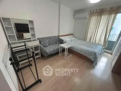 Cozy bedroom with modern decor, featuring a bed, sofa, and vanity near a window with natural light.