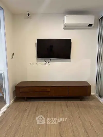 Modern living room with wall-mounted TV and sleek wooden console in a stylish apartment.