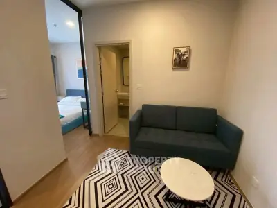 Cozy living room with modern sofa and stylish rug, adjacent to a bedroom.