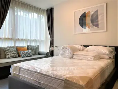 Modern bedroom with large windows, stylish decor, and cozy seating area.