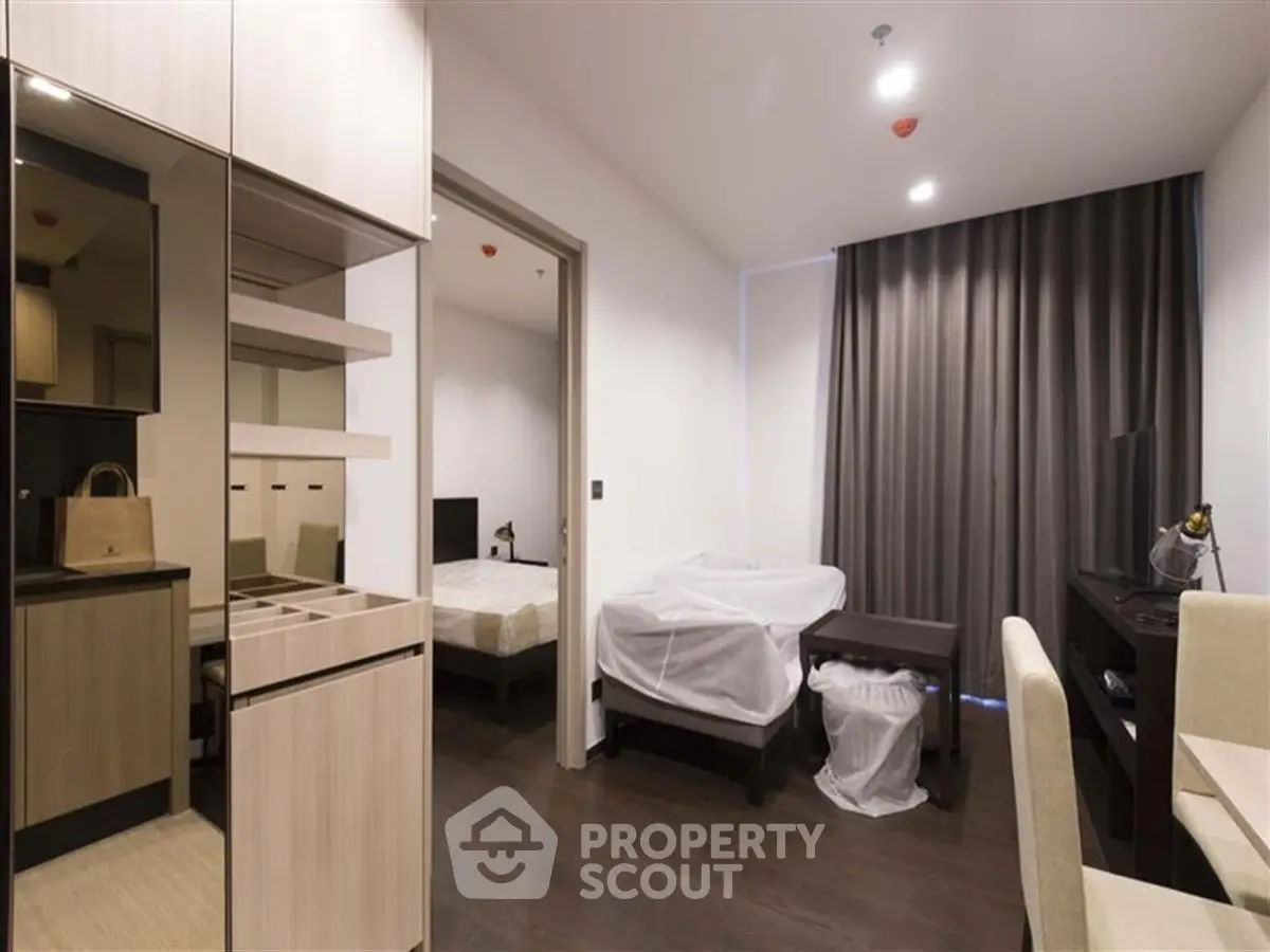 Modern bedroom with sleek furnishings and dark wood flooring in a stylish apartment.