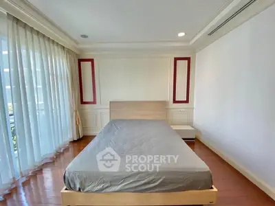 Spacious bedroom with large windows and elegant wooden flooring