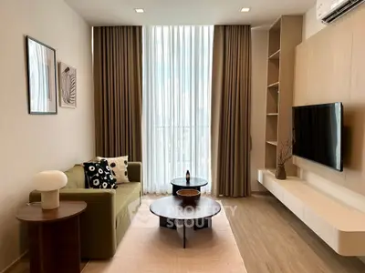 Modern living room with stylish decor and large window offering natural light.
