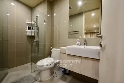 Modern bathroom with glass shower and sleek fixtures in contemporary apartment.