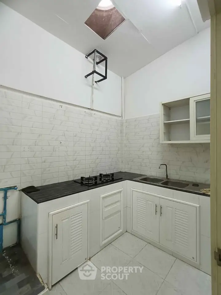 Compact kitchen with white cabinetry and gas stove in modern apartment