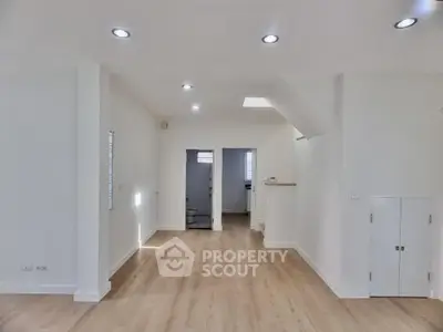 Spacious and bright modern living room with recessed lighting, pristine hardwood floors, and a neutral color palette, perfect for personal customization.