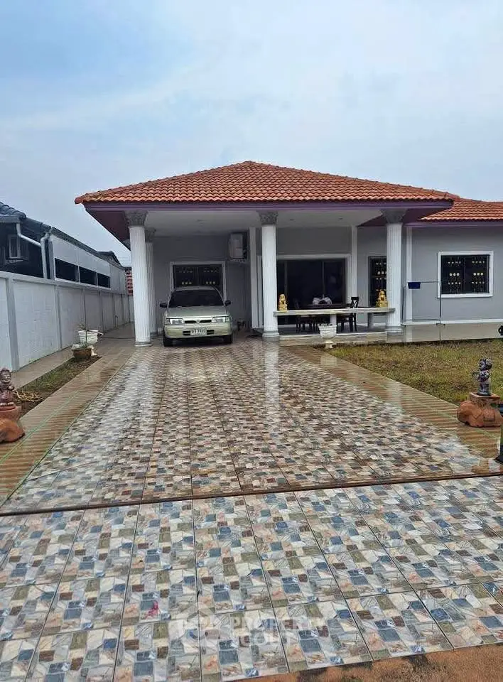 Charming single-story house with tiled driveway and carport, featuring a red-tiled roof and white columns.