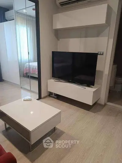 Modern living room with sleek TV unit and mirrored wardrobe in stylish apartment.