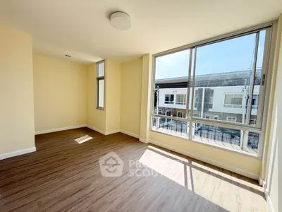 Spacious sunlit room with large windows and modern flooring, perfect for a cozy living space.