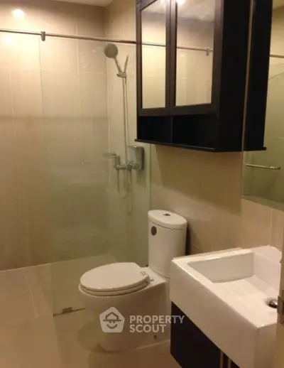 Modern bathroom with glass shower and sleek fixtures in contemporary apartment.