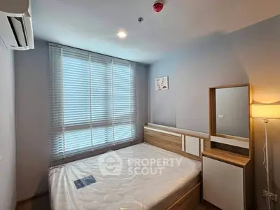 Modern bedroom with natural light, featuring a cozy bed and stylish decor in a contemporary apartment.