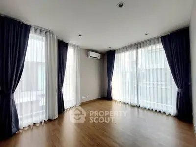 Spacious empty room with large windows and elegant curtains