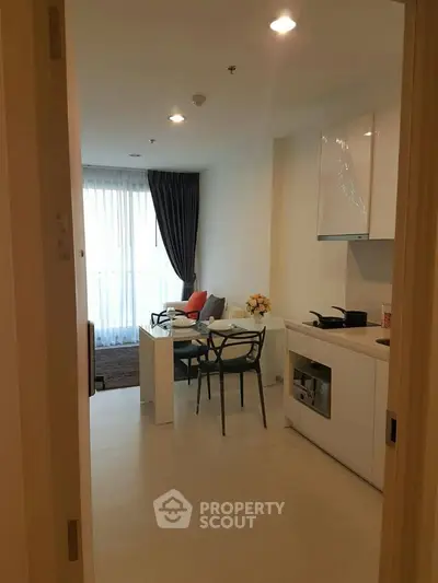 Modern open-layout living room with kitchen, featuring sleek furniture and natural light.