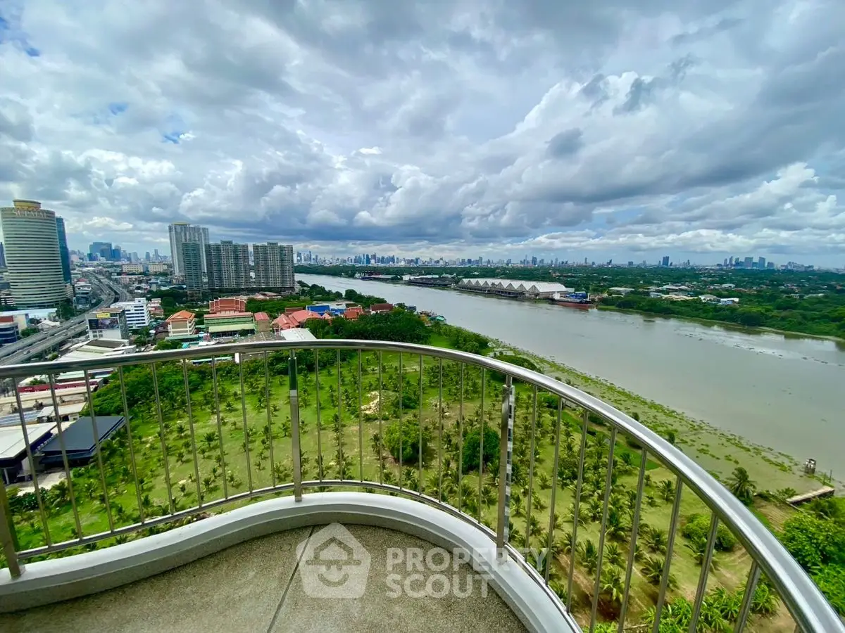 Stunning cityscape view from a high-rise balcony overlooking a river and lush greenery.