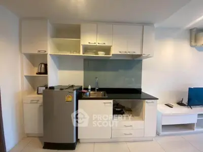 Modern compact kitchen with sleek cabinetry and stainless steel appliances in a cozy apartment.